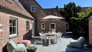 a patio with a table and chairs and an umbrella at Tidal Nest - North Sea Stays in Wenduine
