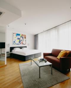a bedroom with a bed and a couch and a coffee table at Augarten Art Hotel, a Member of Design Hotels in Graz