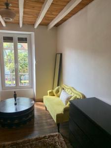 a living room with a yellow couch and a coffee table at Chambres d hôtes H in Lavelanet