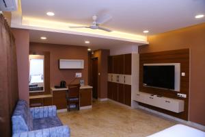 a living room with a couch and a television in a room at Raj Hussain Land Mark Hotel in Mayiladuthurai