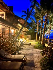 a resort with lounge chairs and palm trees at night at Hekaya Zanzibar in Pingwe
