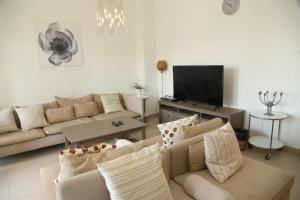 a living room with two couches and a flat screen tv at Samarah Resort Apartment D32 at DeadSea, Sea & Pool view- Families & couples only in Sowayma