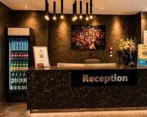 a reception counter in a store with a painting on the wall at Lillys Hotel München in Unterschleißheim