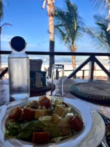 a plate of food on a table with a view of the beach at Hekaya Zanzibar in Pingwe