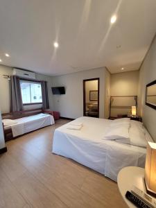 a hotel room with two beds and a desk at Pousada Casa Hospedaria in Paraty