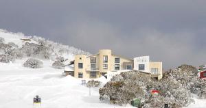 a large building in the snow in front of a mountain at Chalet Hotham 17 in Mount Hotham