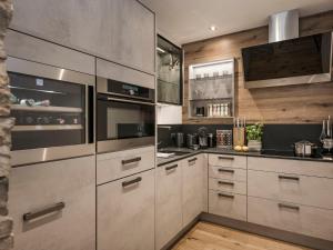 a kitchen with stainless steel appliances and wooden walls at Landhaus Mader Hintertux in Tux