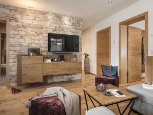 a living room with a tv on a stone wall at Landhaus Mader Hintertux in Tux