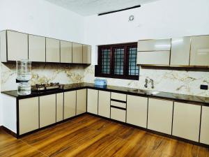 a kitchen with white cabinets and a wooden floor at Nilavu villas in Alleppey