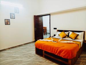 a bedroom with a bed with orange sheets and yellow pillows at Nilavu villas in Alleppey