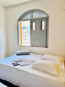 a bedroom with a white bed with a window at Hotel Dairy Walley in Itapetinga