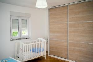 a baby room with a crib and a sliding glass door at Apartman VITINA in Ljubuški