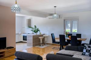 a living room with a table and chairs and a kitchen at Apartman VITINA in Ljubuški