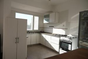 a white kitchen with white cabinets and a window at Casa Juanca in Comodoro Rivadavia