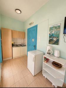 eine Küche mit blauer Tür und weißem Kühlschrank in der Unterkunft Sevasti Studios in Panormos Kalymnos