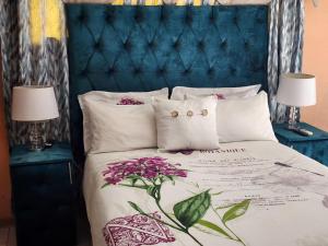a bedroom with a bed with a blue headboard and purple flowers at PJ Guesthouse in Welkom