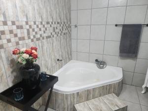 a bathroom with a bath tub with a vase of flowers at PJ Guesthouse in Welkom