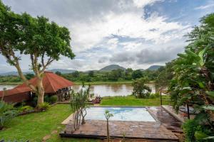 a resort with a swimming pool next to a river at River House Lodge in Malelane