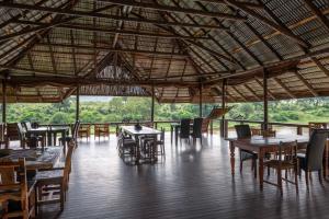 a restaurant with tables and chairs and a large roof at River House Lodge in Malelane