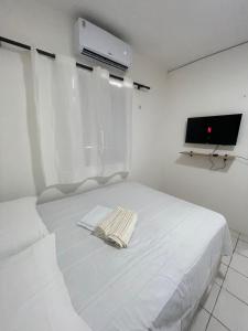 a white bedroom with a bed and a tv at Hospedagem Sousa in Santa Inês