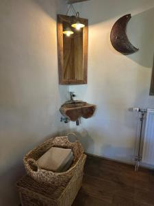 a bathroom with a sink and a mirror and a basket at L'Alterre Durbuy in Durbuy