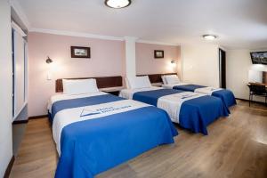 three beds in a room with blue and white sheets at HOTEL AMERICANA PASTO in Pasto