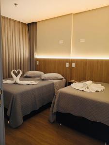 a hotel room with two beds with swans on them at Flats New York Meia Praia Itapema in Itapema +31 photos