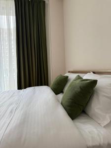 a white bed with green pillows next to a window at N4 Alvina Complex in Tsaghkadzor +14 photos