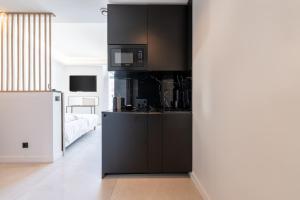 a kitchen with black cabinets and a microwave at Suite luxe jacuzzi - CANNES SUQUET in Cannes