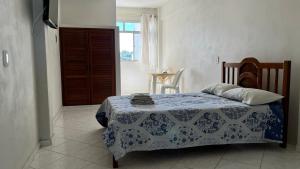 a bedroom with a bed with a blue and white blanket at Hotel Polonini in Piúma