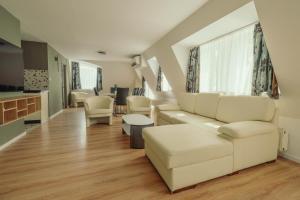 a living room with white furniture and a kitchen at Caesar Apartments & Rooms in Siófok