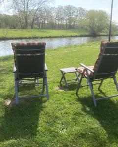 two chairs sitting in the grass near a pond at Mietwohnwagen E2 am Flussufer in Wienhausen