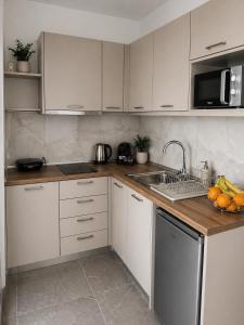 a kitchen with white cabinets and a sink with fruit on the counter at Haraki Emerald in Haraki