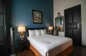 a bedroom with a large white bed with two lamps at Hotel Casino Morelia in Morelia