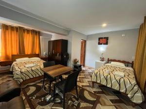 a hotel room with two beds and a table at Hotel las vegas in Huánuco