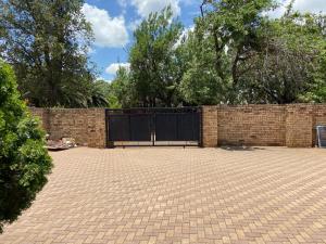 a brick fence with a black gate and a brick driveway at Highway Haven in Stilfontein