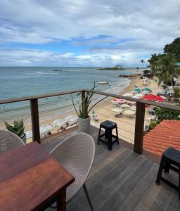 a balcony with a table and chairs and a beach at Pousada Manhã Dourada in Morro de São Paulo