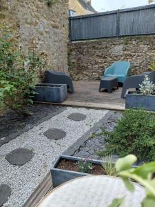 a garden with chairs and plants and a stone wall at Comme à la maison in Ernée