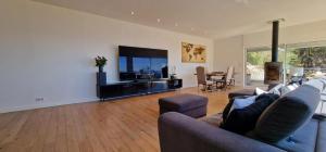 a living room with a couch and a flat screen tv at Villa Azur Horizon in La Turbie