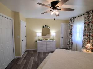 a bedroom with a ceiling fan and a dresser with a mirror at By Summersville Lake 3BR Jetted Tub Sauna in Craigsville
