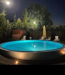 a swimming pool at night with chairs and an umbrella at Mierzeja Bliss Point - Basen, Parking, Grill in Sztutowo +9 photos