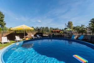 a large swimming pool with chairs and an umbrella at Mierzeja Bliss Point - Basen, Parking, Grill in Sztutowo