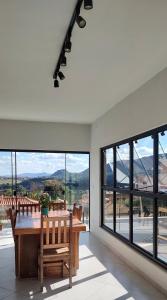 a dining room with a table and large windows at Casa De Valentina in Tiradentes