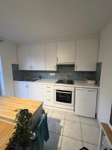 a kitchen with white cabinets and a wooden table at Seaward Cottage met Jacuzzi in De Haan +19 photos