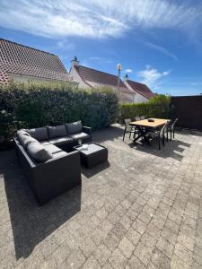 a patio with a couch and a table and a tableablish at Seaward Cottage met Jacuzzi in De Haan