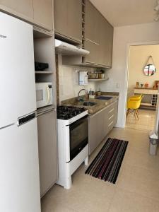 a kitchen with a stove and a white refrigerator at Lisboa Hospedaria 300 m da praia do forte in Cabo Frio