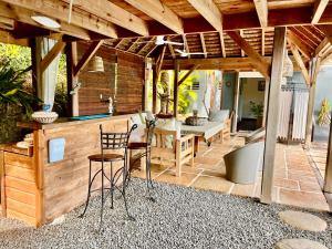 a patio with a bar with chairs and a table at La Voile Grise - Villa de charme - Sea View in Le Gosier