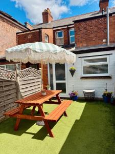 a wooden picnic table with an umbrella on a lawn at 31 Sailsbury road in Marlborough