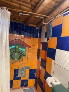 a bathroom with a colorful tiled wall with a toilet at Hotel Casa Tarzan San Agustin in San Agustín