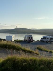 three vehicles parked in a parking lot next to a body of water at North Cape Accommodation, Norway in Repvåg +3 photos